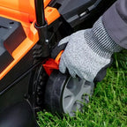 Person wearing a glove adjusting a lawn mower on grass