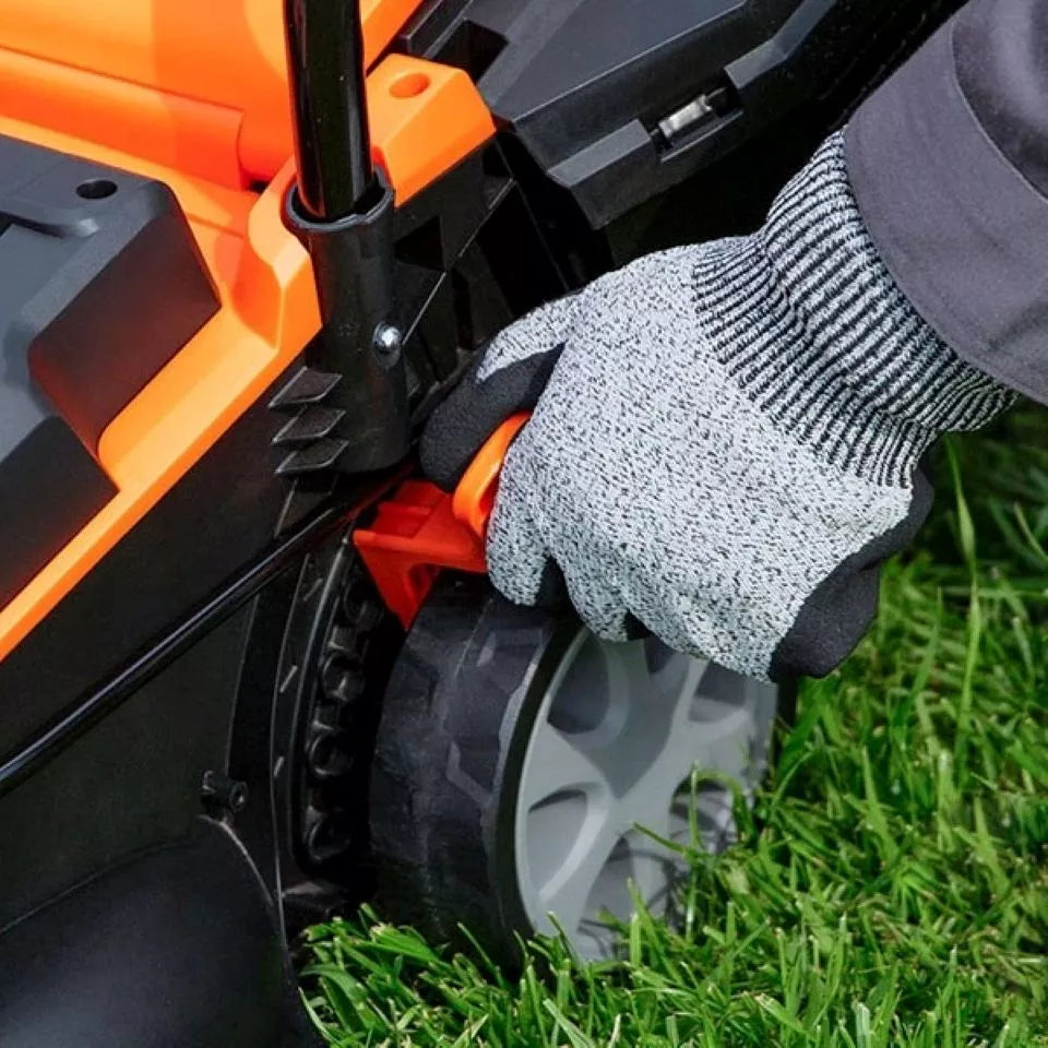 Person wearing a glove adjusting a lawn mower on grass