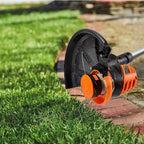 Gardening tool, possibly a weed wacker, being used on grass with a blurred background.