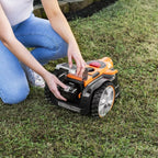 Person adjusting a robotic lawn mower on grass