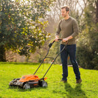 Man using a lawn mower on a grassy area with trees in the background