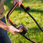 Person holding a cordless grass trimmer on a grassy background