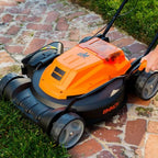 Orange and black lawn mower on a brick path with grass