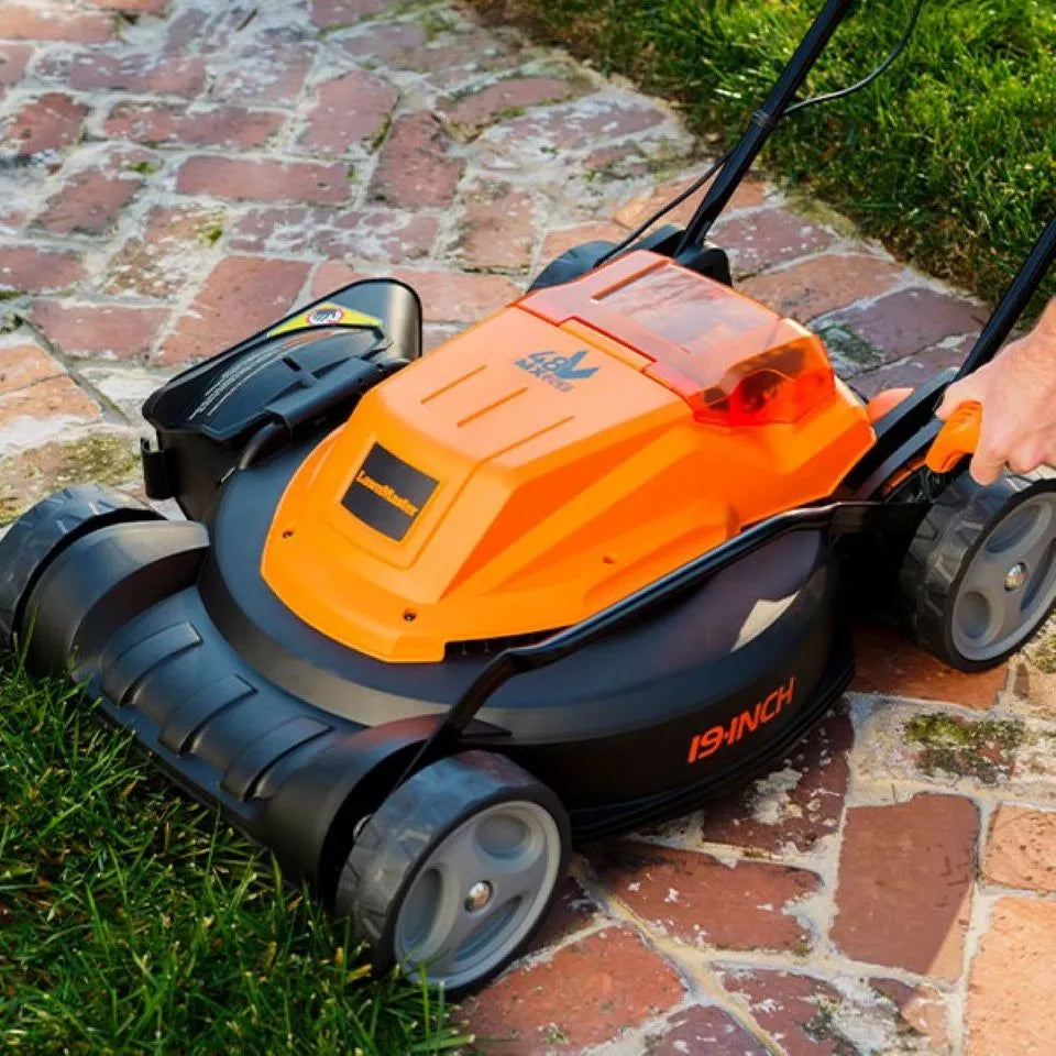 Orange and black lawn mower on a brick path with grass