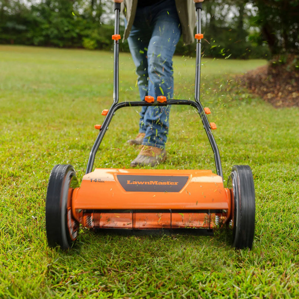 Person using a LawnMaster lawn mower on a grassy area
