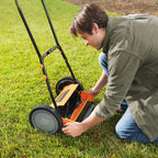 Person adjusting a lawn mower on a grassy area