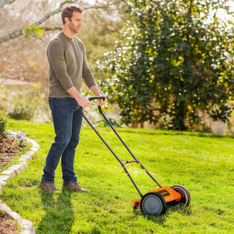 Man mowing grass with a lawn mower in a garden setting