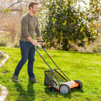 Man mowing a lawn with a push mower in a garden setting