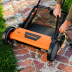 Person pushing a LawnMaster lawn mower on a brick patio