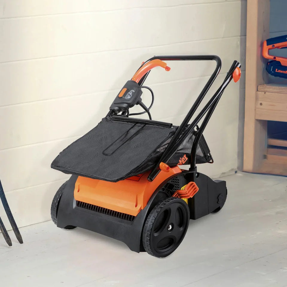 Orange and black snow blower on a white floor with a light-colored wall in the background.