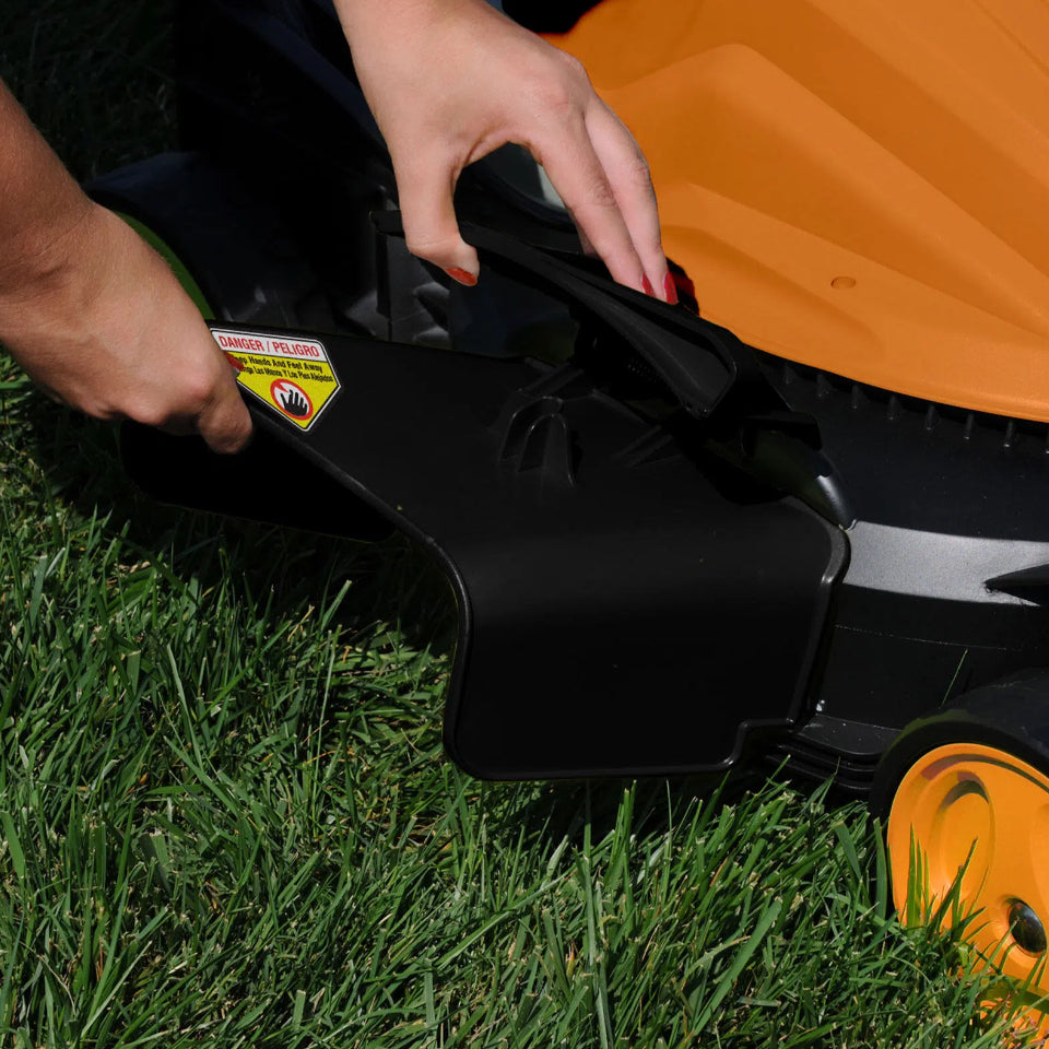 Person adjusting a black lawn mower deck on grass
