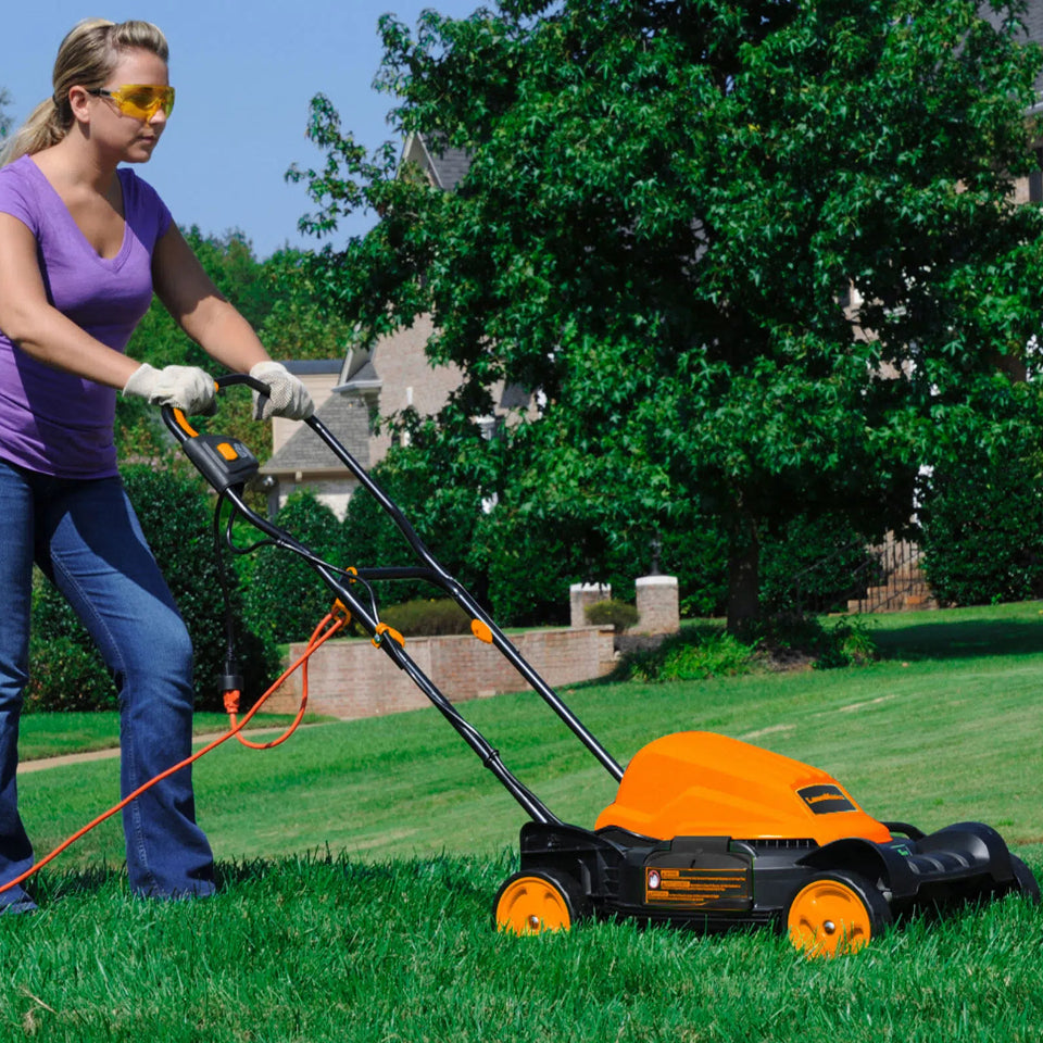 Woman mowing a lawn with a push mower on a sunny day.