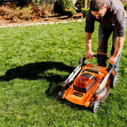 Man using a lawn mower on a green lawn