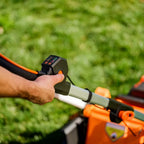 Person operating a lawn mower with a close-up of the handle and grass in the background