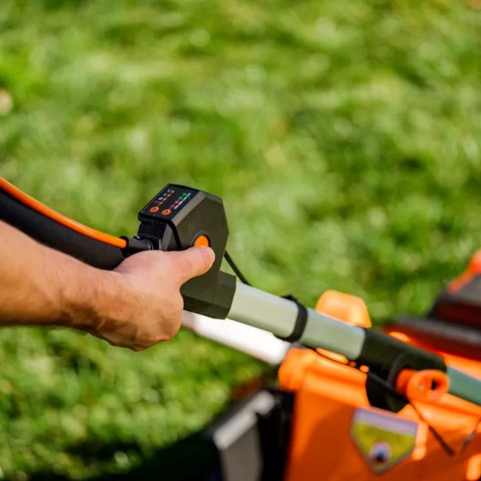 Person operating a lawn mower with a close-up of the handle and grass in the background
