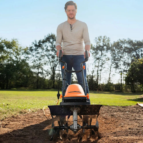 Man operating a tiller in a garden with trees in the background