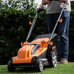 Person using an orange and black lawn mower on grass with a blurred background