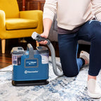 Person using a Vacmaster Spot Cleaner on a rug in a living room.