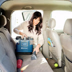 Woman using a vacuum cleaner in the back seat of a car