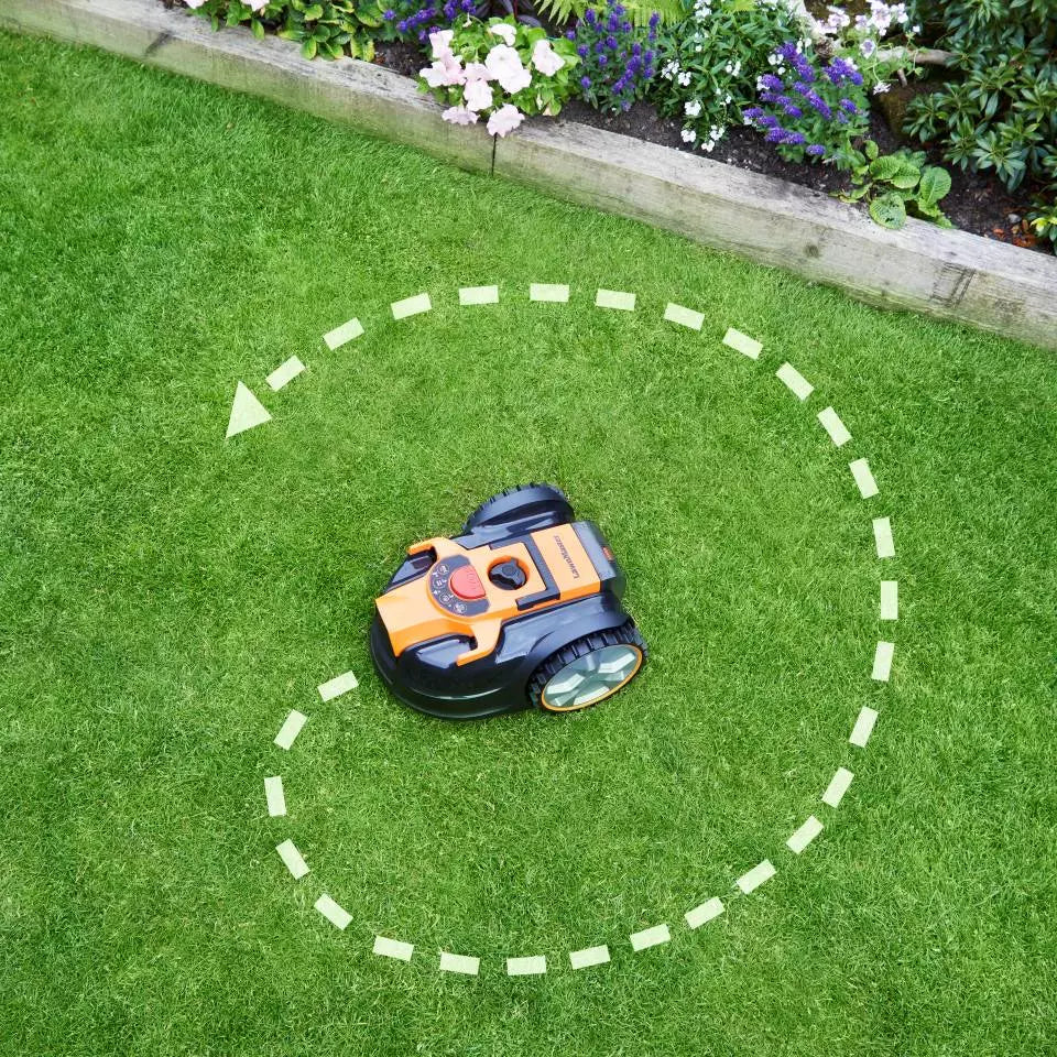 Robotic lawn mower on a green lawn with a circular path marked around it.