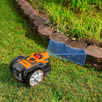 Robotic lawn mower on grass with a clear path indicated by a blue line.