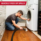Person cleaning a wooden floor with a vacuum cleaner in front of a washing machine.