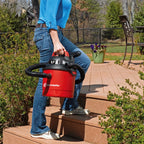 Person holding a red and black vacuum cleaner on outdoor steps