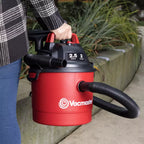 Red Vacmaster vacuum cleaner being held by a person outdoors.