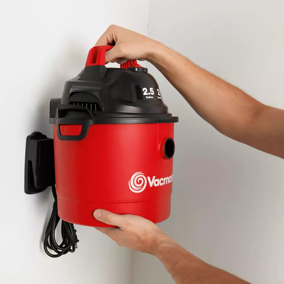 Red and black vacuum cleaner with a person holding it against a white wall